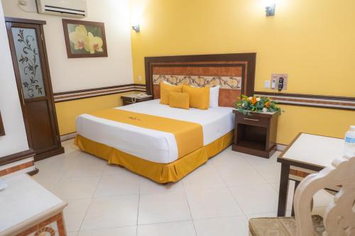 a hotel room with a large bed with yellow walls at Villa Las Margaritas Caxa in Xalapa