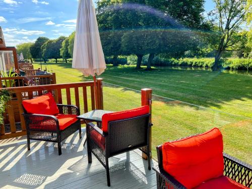 a patio with a table and chairs and an umbrella at Riverbank Lodge in Stratford-upon-Avon