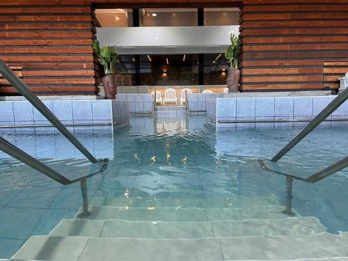 a swimming pool with chairs and water in a building at Aguas del Monte Hotel&Spa in Tomé