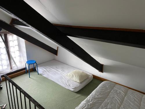 Cette chambre comprend deux lits et un tabouret bleu. dans l'établissement La petite maison dans le jardin, à Bournazel