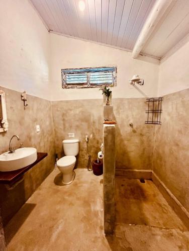 a dirty bathroom with a toilet and a sink at Pousada Jardim da Praça in Caraíva