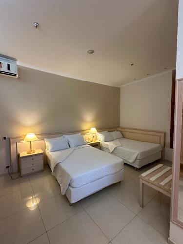 two beds in a hotel room with two lamps at Hotel Saint Paul in Sao Jose do Rio Preto