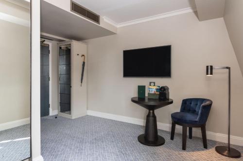 a room with a table and a chair and a television at Kimpton Fitzroy London by IHG in London