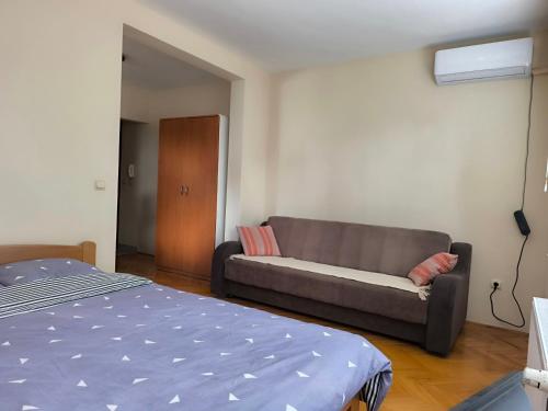 una sala de estar con un sofá y una cama en REA APARTMENT, en Kragujevac