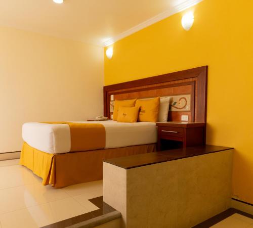 a hotel room with a bed with yellow walls at Villa Las Margaritas Caxa in Xalapa
