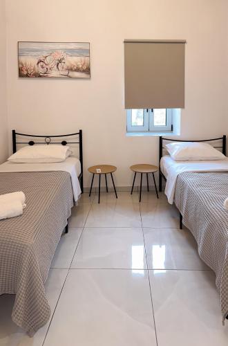 two beds in a room with two tables at Thetis, the Beach House in Nafplio
