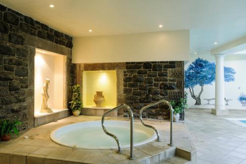 a large bathroom with a tub in a stone wall at Tre-Ysgawen Hall & Spa in Llangefni