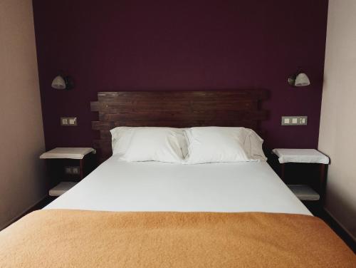 a bedroom with a large white bed with two tables at Hotel Vitorio in Cudillero