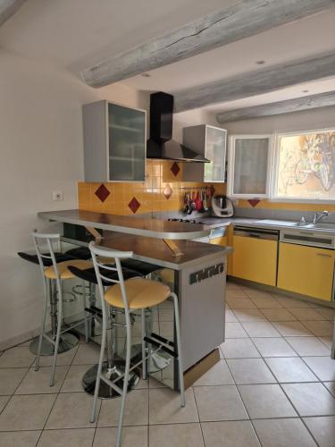- une cuisine avec un îlot doté de tabourets de bar dans l'établissement Maison de campagne à 2km de lourmarin, à Puyvert