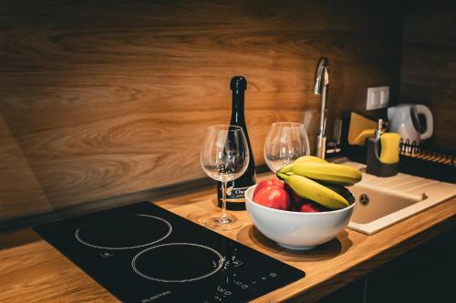 Un mostrador con un bol de fruta y dos copas de vino. en Diamond Light Apartments, en Nikiti