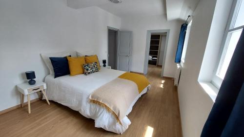 - une chambre dotée d'un grand lit avec des oreillers jaunes et bleus dans l'établissement Aux'Cerfs - Vue cathédrale, à Auxerre