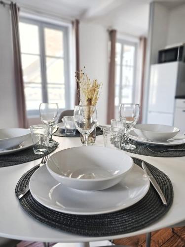 une table avec une plaque blanche et des verres sur celle-ci dans l'établissement Aux'Cerfs - Vue cathédrale, à Auxerre