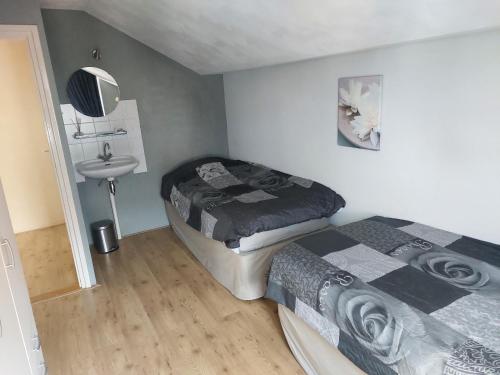 a small bedroom with two beds and a sink at Strandhuis in Katwijk aan Zee in Katwijk aan Zee