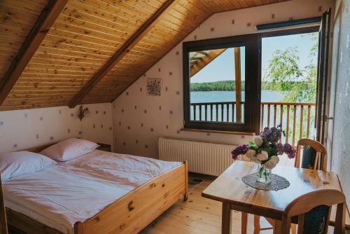 a bedroom with a bed and a table and a window at Agroturystyka nad jeziorem-Herrmann hof in Dejguny