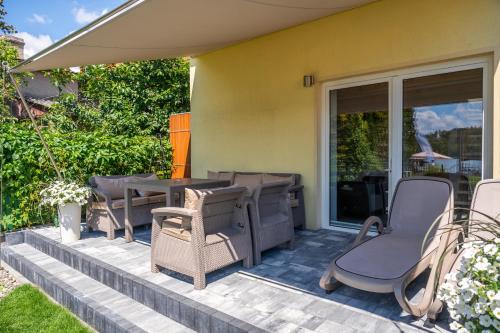 a patio with chairs and a table and glass doors at Promenada Apartamenty i Domek Nad Jeziorem in Mikołajki