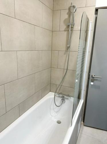 La salle de bains est pourvue d'une baignoire et d'une douche avec une porte en verre. dans l'établissement RS-0 - Appartement F2 au RDC à Mulhouse pour 1-3 pers, à Mulhouse