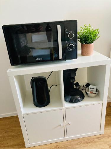 un micro-ondes sur un support de micro-ondes blanc dans l'établissement Studio Cosy en centre-ville, à Saint-Brieuc