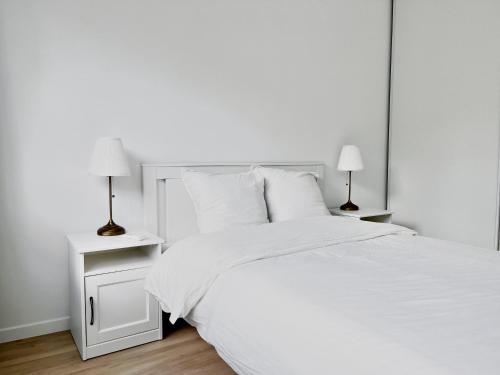 - une chambre blanche avec un lit blanc et deux lampes dans l'établissement Charmant Appartement au Cœur du 13ème Arrondissement de Paris, à Paris