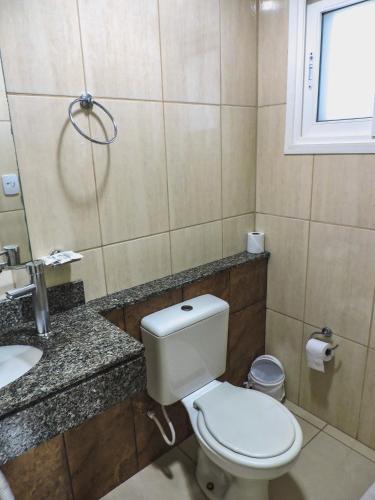 a bathroom with a toilet and a sink at Coimbra Hotel Pousada in Pelotas