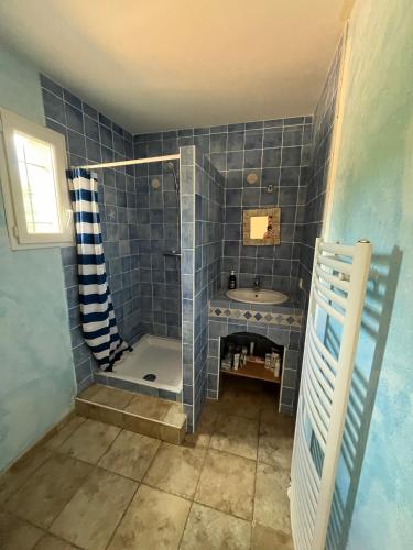 La salle de bains est pourvue de carrelage bleu, d'une douche et d'un lavabo. dans l'établissement Charming villa surrounded by nature, à Simiane-Collongue