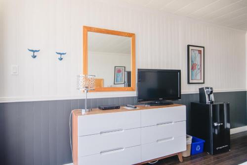 a room with a dresser with a tv and a mirror at Riôtel Carleton-sur-Mer in Carleton sur Mer