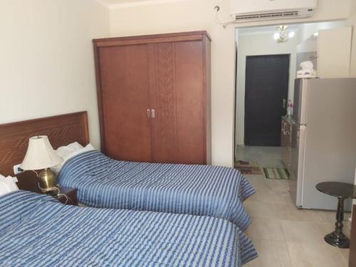 une chambre avec deux lits et un placard avec un réfrigérateur dans l'établissement Aqua View Resort studio, North Coast, منتجع اكوا فيو الساحل الشمالي, à El Qasaba esh Sharqīya