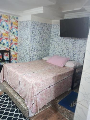 a bedroom with a bed with a tv on the wall at Suites casa da lucia in Salvador