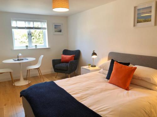 a bedroom with a bed and a table and a chair at Guest Room with Parking Near St Ives & Penzance in Penzance
