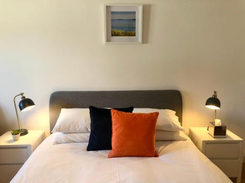 a bed with an orange pillow on top of it at Guest Room with Parking Near St Ives & Penzance in Penzance