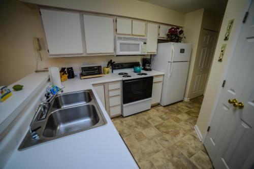a kitchen with white cabinets and a sink and refrigerator at Litchfield Beach & Golf Resort in Pawleys Island