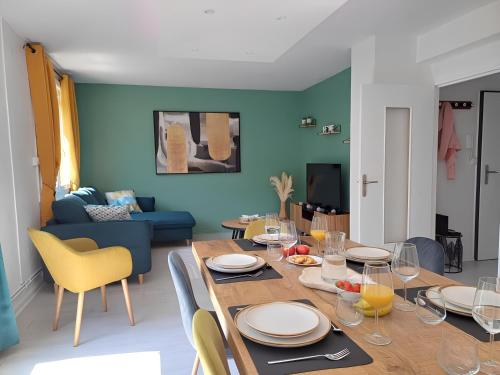 - un salon doté d'une table en bois avec des assiettes et des chaises dans l'établissement Proche CHU - 4 couchages - Parking gratuit - Local vélo, à Amiens