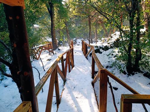 a wooden fence in the snow with benches at Cabañita Del Árbol Concón in Nevados de Chillan