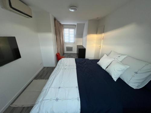 - une chambre avec un lit doté d'une couverture bleue et d'oreillers dans l'établissement Maison Paris JO 2024, à Garges-lès-Gonesse