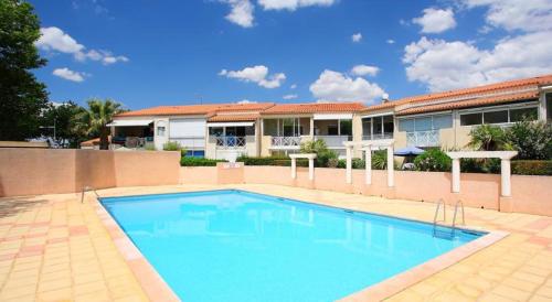 une grande piscine bleue devant un immeuble dans l'établissement Le petit Nid du Soleil, au Cap d'Agde