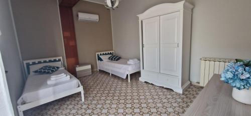 - une chambre avec 2 lits et une armoire blanche dans l'établissement La terrazza sulle Eolie, à Capo dʼOrlando