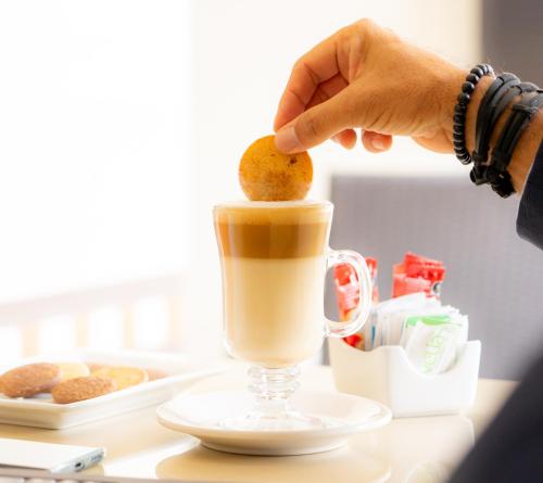 a person putting a cookie in a cup of coffee at Centro Hotel Villa las Margaritas in Xalapa