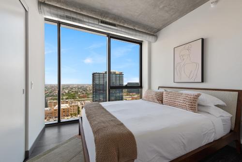 a bedroom with a large bed and large windows at Fulbrix Bright Designer Apartments with West Loop Views in Chicago
