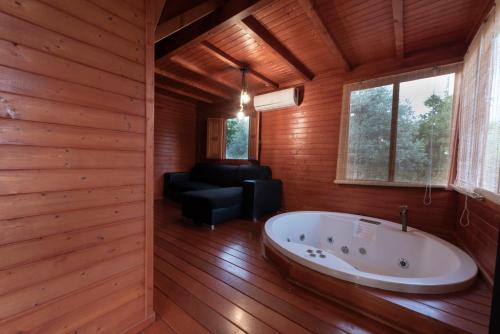 a bathroom with a tub in a room with wooden walls at El jardín del Edén in Órgiva