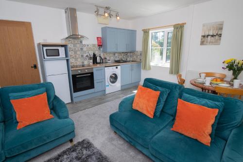 a living room with two blue couches and a kitchen at Kibbletree Cottage in Bridlington