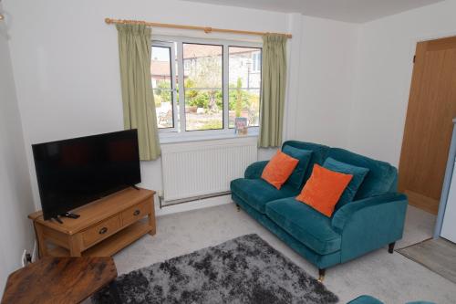 a living room with a blue couch and a television at Kibbletree Cottage in Bridlington