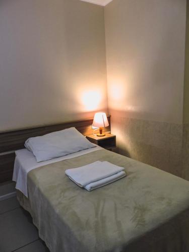 a bedroom with a bed with two towels on it at Coimbra Hotel Pousada in Pelotas