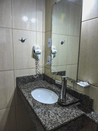 a bathroom counter with a sink and a mirror at Coimbra Hotel Pousada in Pelotas