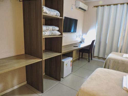 a room with a desk in a hotel room at Coimbra Hotel Pousada in Pelotas