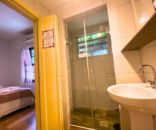 a bathroom with a glass shower and a sink at Pousada Papaya Container in Ubatuba