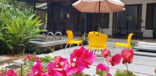a patio with two chairs and an umbrella and pink flowers at Villa Akala in Cocles
