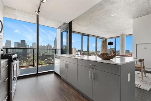 a kitchen with white cabinets and large windows at Fulbrix Bright Designer Apartments with West Loop Views in Chicago