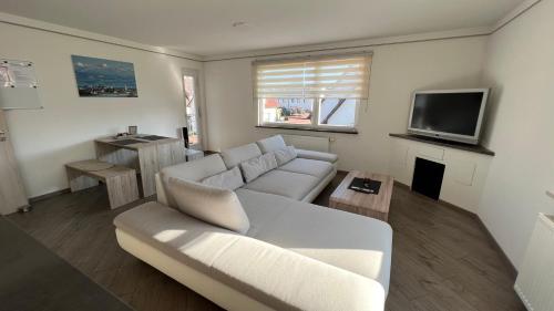 a living room with a white couch and a tv at David´s Apartment in Meckenbeuren