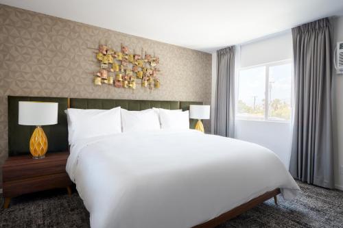 a bedroom with a large white bed and a window at The Cole in Palm Springs