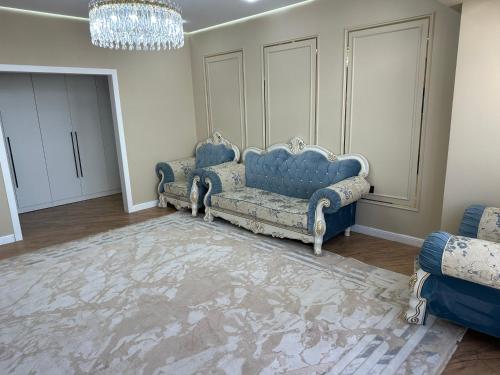 a living room with two blue couches and a chandelier at Квартира in Atyraū