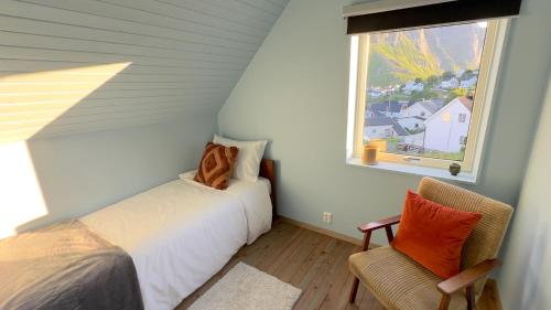 a bedroom with a bed and a chair and a window at Reine Superior Panorama House in Reine